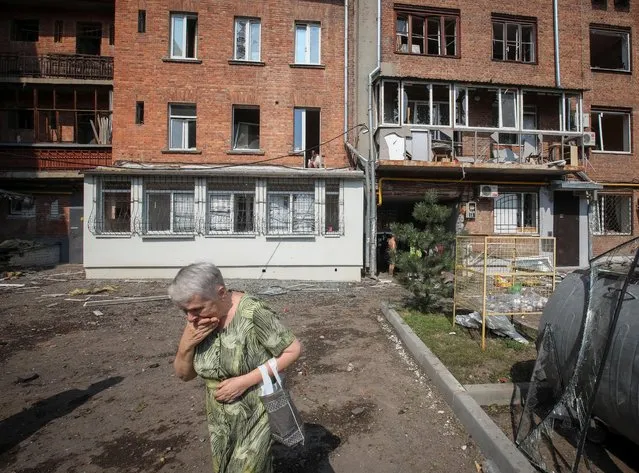 A woman walks in a front of residential building damaged by a Russian military strike, as Russia's attack on Ukraine continues, in Kharkiv, Ukraine on August 11, 2022. (Photo by Vyacheslav Madiyevskyy/Reuters)