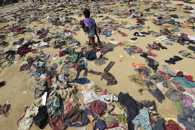 A Rohingya Muslim boy walks past discarded clothing on the ground at the Bhalukali refugee camp near Ukhia on September 16, 2017. According to the UN nearly 400,000 Rohingya have arrived in Bangladesh since August 25 after fleeing a military crackdown launched by Myanmar's military in response to attacks by Rohingya rebels. (Photo by Dominique Faget/AFP Photo)