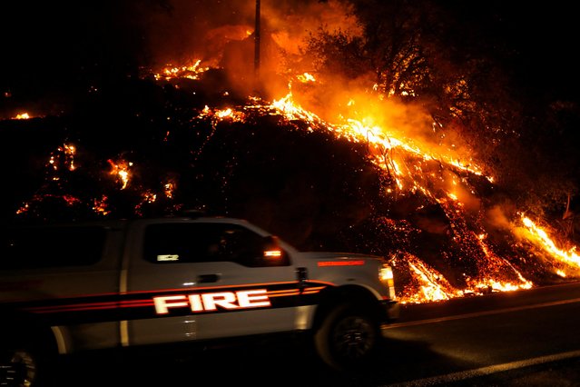 A firefighting vehicle passes by the flames from Wishon Fire as it burns near Springville, California, U.S., August 15, 2022. (Photo by David Swanson/Reuters)