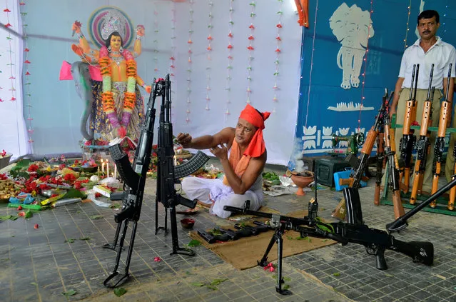 A Hindu priest worships in front of weapons belonging to India's Tripura State Rifles during the Vishwakarma Puja or the festival of the Hindu deity of architecture and machinery in Agartala, India, September 17, 2017. (Photo by Jayanta Dey/Reuters)