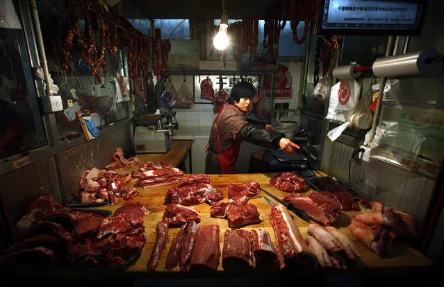 A woman points for a customer, to cuts of pork for sale at her small stall located in a meat market in central Beijing, January 6, 2012. The price of pork in China could soon rival U.S. payrolls as the world's most watched economic indicator. International investors are increasingly focused on domestic demand in the world's second-largest economy as their key measure of global economic health. (Photo by David Gray/Reuters)