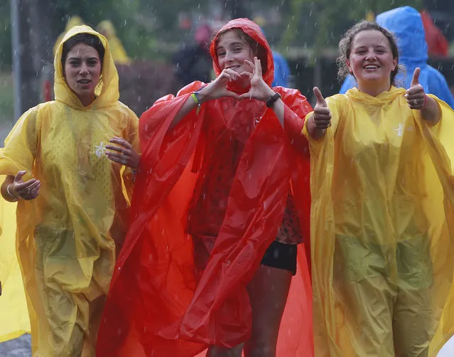 Young women from France are among the dozens of thousands of young people from around the globe walking in thunderstorm to the site of a Catholic Mass in the Blonia green in Krakow, Poland, Tuesday, July 26, 2016 that will officially open the World Youth Day, a major gathering of Catholics that will be joined by Pope Francis on Wednesday. (Photo by Czarek Sokolowski/AP Photo)