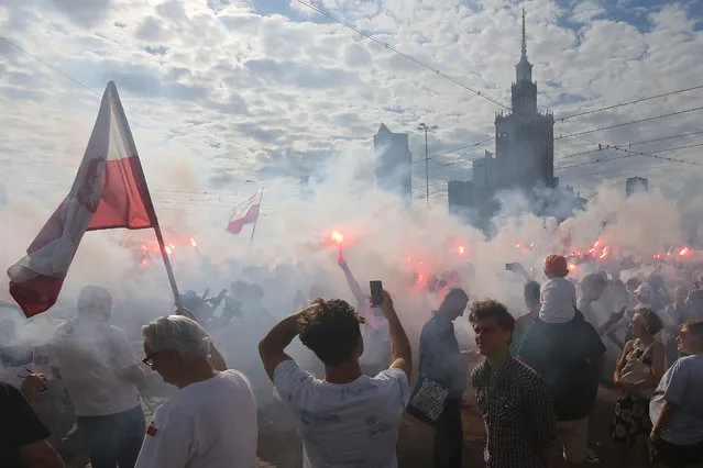People stand on the city's main intersection holding burning flares to commemorate the 72nd anniversary of the 1944 Warsaw Uprising in Warsaw, Poland, Monday, August 1, 2016. Thousands of young city residents opened an uneven struggle on Aug. 1, 1944 in an effort to liberate the city from the Nazis and take control ahead of the advancing Soviet Red Army. (Photo by Czarek Sokolowski/AP Photo)