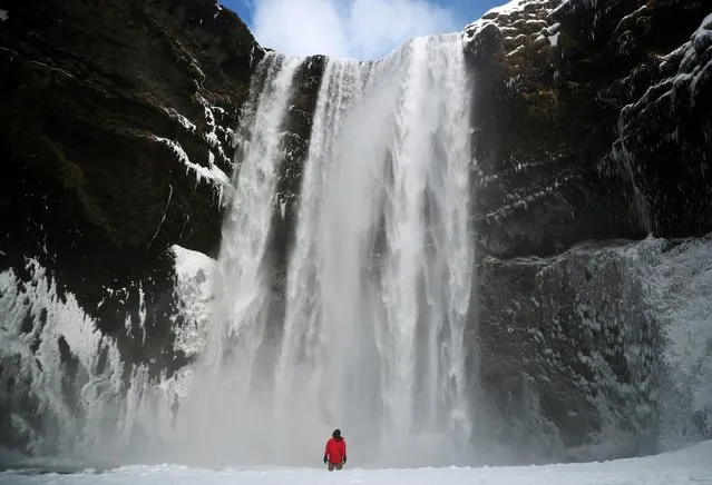 A man stands in front of the Skogafoss waterfall in Skogar, Iceland on March 8, 2020. (Photo by Hannah McKay/Reuters)
