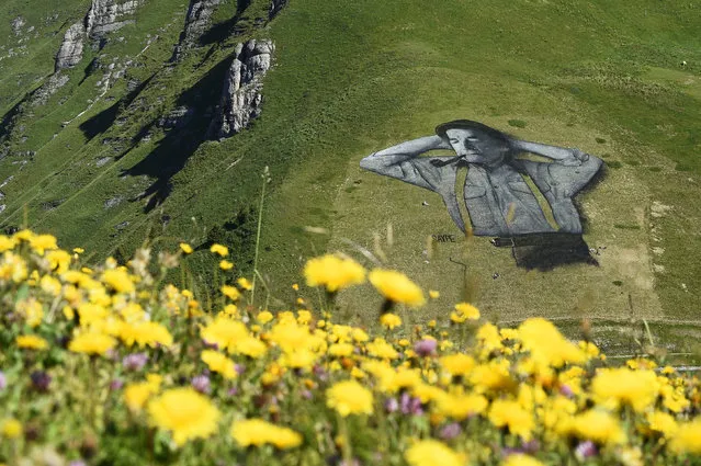 A painting, created by French artist Saype and said to be the world's largest biodegradable painting is seen on the Chaux-de-Mont ski slope above the Alp resort of Leysin on August 4, 2016. The 100 meter long and 100 meter large painting is made with flour, linseed oil, water and biodegradable natural pigments. (Photo by Alain Grosclaude/AFP Photo)