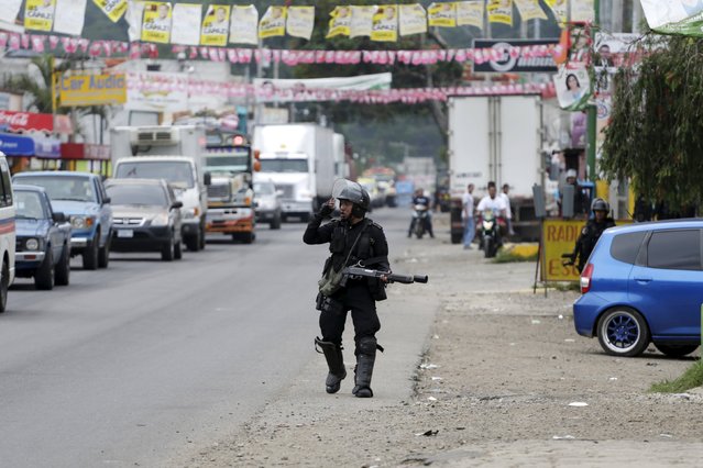 A riot police officer walks during a protest against the re-election of the city's mayor Rubelio Recinos of the Patriot Party in Barberena, northwest of Guatemala City, September 8, 2015. (Photo by Jorge Dan Lopez/Reuters)