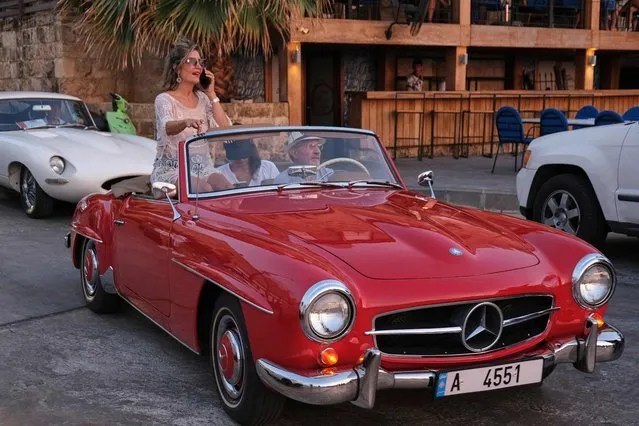 A woman talks on the phone as she sits in her 1961 Mercedes Benz during a classic and luxury car parade at the fishermen's port of the northern Lebanese city of Batroun, on August 6, 2022. (Photo by Ibrahim Chalhoub/AFP Photo)