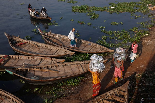 Female hawkers carry utensils as they arrive at a ferry station in the winter morning to cross the Buriganga River, in Dhaka, Bangladesh on December 17, 2024. (Photo by Mohammad Ponir Hossain/Reuters)