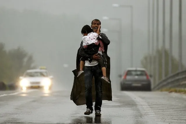 A Syrian refugee screams at others to wait for him as he carries his daughter through a rainstorm towards Greece's border with Macedonia, near the Greek village of Idomeni, September 10, 2015. (Photo by Yannis Behrakis/Reuters)