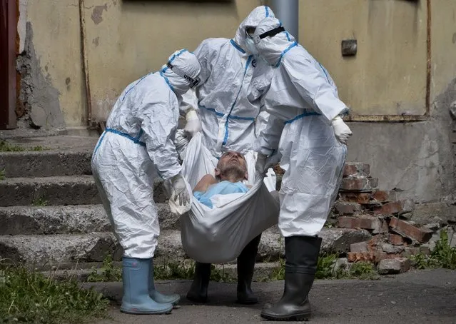 Medical workers wearing protective gear to protect against coronavirus infection, carry a patient at infectious diseases hospital where patients with coronavirus are treated in St.Petersburg, Russia, Wednesday, June 3, 2020. (Photo by Dmitri Lovetsky/AP Photo)