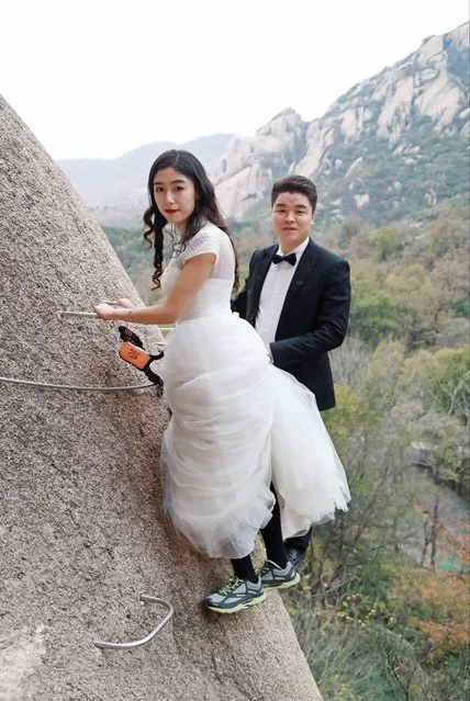 A newlywed couple dangling from a cliff face poses for wedding photos at the Chaya Mountain scenic spot on November 11, 2017 in Zhumadian, Henan Province of China. (Photo by Sipa Asia/Rex Features/Shutterstock)