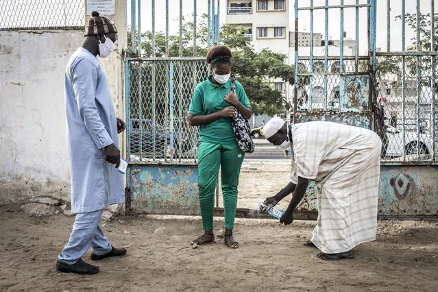 A High School student at the Lycee Blaise Diagne gets her feet disinfected as she arrives for her first day back at school in Dakar on June 25, 2020. Schools have been closed since early March 2020 due to the outbreak of the COVID-19 coronavirus in Senegal. (Photo by John Wessels/AFP Photo)