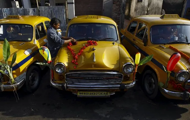 A driver decorates his yellow ambassador taxi to celebrate the festival of Vishwakarma Puja or the festival of the Hindu deity of architecture and machinery, outside a temple in Kolkata, India, September 18, 2015. During the festival, most of the vehicles and machines are decorated and prayers are offered for trouble-free working and good business all the year. (Photo by Rupak De Chowdhuri/Reuters)