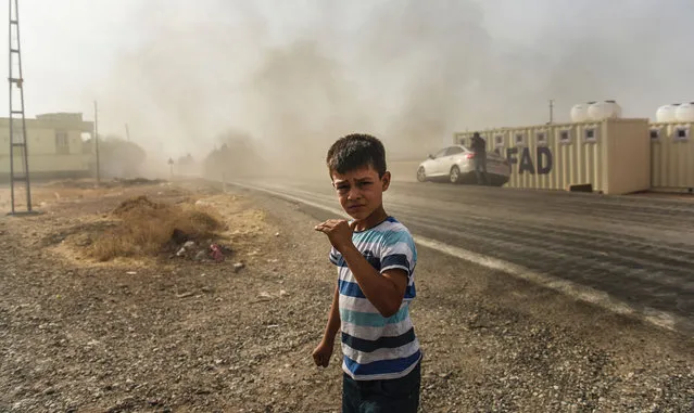 This picture taken around 5 kilometres west from the Turkish Syrian border city of Karkamis in the southern region of Gaziantep, on August 25, 2016 shows a boy looking on as Turkish Army tanks drive to the Syrian Turkish border town of Jarabulus. Turkey's army backed by international coalition air strikes launched an operation involving fighter jets and elite ground troops to drive Islamic State jihadists out of a key Syrian border town. The air and ground operation, the most ambitious launched by Turkey in the Syria conflict, is aimed at clearing jihadists from the town of Jarabulus, which lies directly opposite the Turkish town of Karkamis. (Photo by Bulent Kilic/AFP Photo)