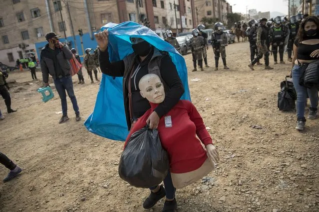 A street vendor walks away with her mannequin during a police operation to evict a group of street vendors who came out to sell their products, ignoring lockdown measures to curb the spread of the new coronavirus, in La Victoria district, in Lima, Peru, Tuesday, June 16, 2020. (Photo by Rodrigo Abd/AP Photo)
