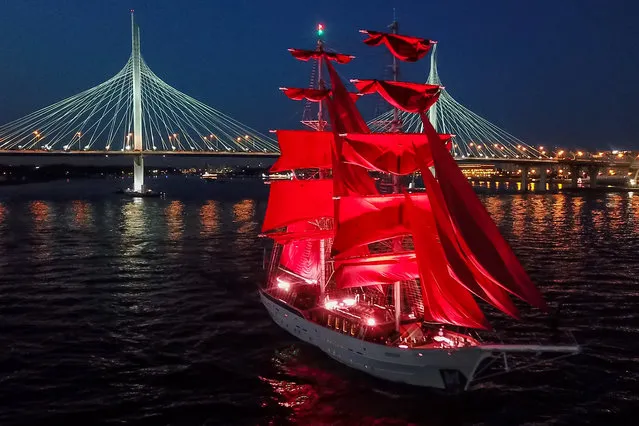 The Rossiya (Russia) brig sails in the Gulf of Finland  in St Petersburg on June 26, 2020 during a rehearsal of the “2020 Scarlet Sails Festival” for high school graduates. This year, the event will be held online amid the COVID-19 coronavirus pandemic. Seen in the background is a cable-stayed bridge on the Western High-Speed Diameter. (Photo by Peter Kovalev/TASS)
