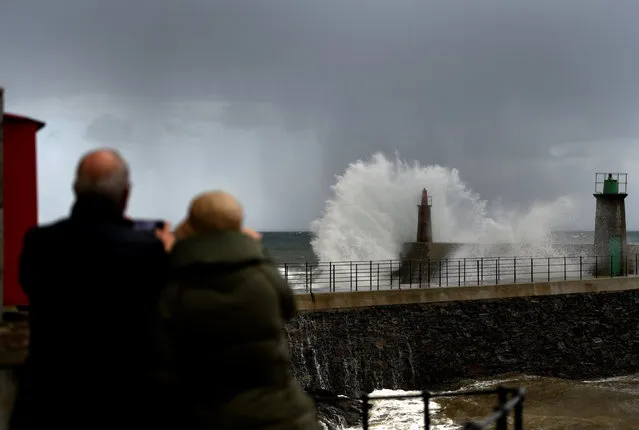People take pictures as huge waves crash on the Viavelez seafront in the northern Spanish region of Asturias, Spain, December 11, 2017. (Photo by Eloy Alonso/Reuters)
