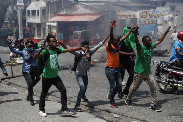 Demonstrators raise their hands as they approach police officers during a protest against gang-related violence and to demand the resignation of Haiti's transitional presidential council, in Port-au-Prince, Haiti, on March 26, 2025. (Photo by Jean Feguens Regala/Reuters)