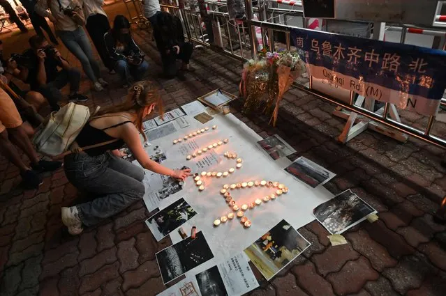 Students light candles on the campus of the Chinese University of Hong Kong, in solidarity with protests held on the mainland over Beijing's Covid-19 restrictions, in Hong Kong on November 28, 2022. Hundreds of people have taken to the streets in China's major cities in a rare outpouring of public anger against the state over its zero-Covid policy. (Photo by Peter Parks/AFP Photo)
