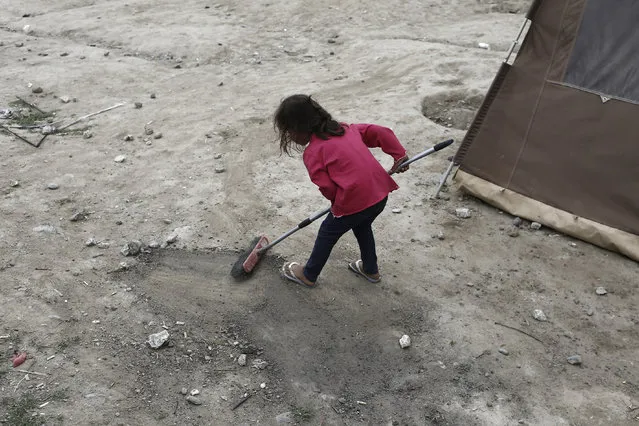 A girl uses a broom at a makeshift camp for refugees and migrants at the Greek-Macedonian border near the village of Idomeni, Greece, May 19, 2016. (Photo by Kostas Tsironis/Reuters)
