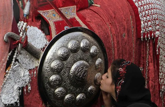 A Pakistani Shi'ite Muslim girl kisses a religious motif of sword and shield during procession to commemorate Ashoura in Rawalpindi November 4, 2014. (Photo by Faisal Mahmood/Reuters)