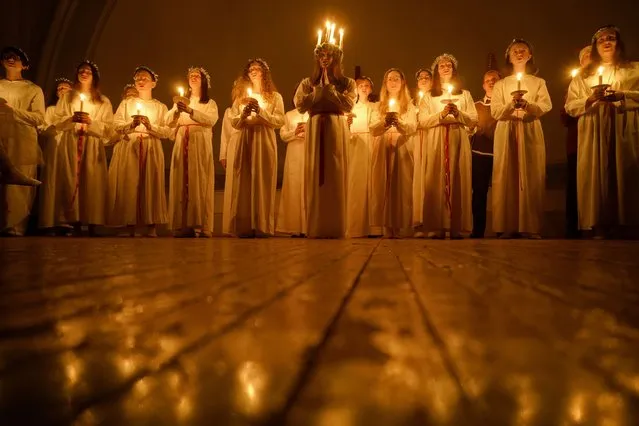 Young women sing carols as they hold candles to celebrate St. Lucia's Day in the Evangelical Lutheran Church of Saint Catherine in St.Petersburg, Russia, Tuesday, December 13, 2022. The Church was built in the 19th century by and for Swedish expatriates in Saint Petersburg, and it is usually called the Swedish church. In the Soviet era the Church was used as a sport hall. St. Lucia is the patron saint of vision. (Photo by Dmitri Lovetsky/AP Photo)