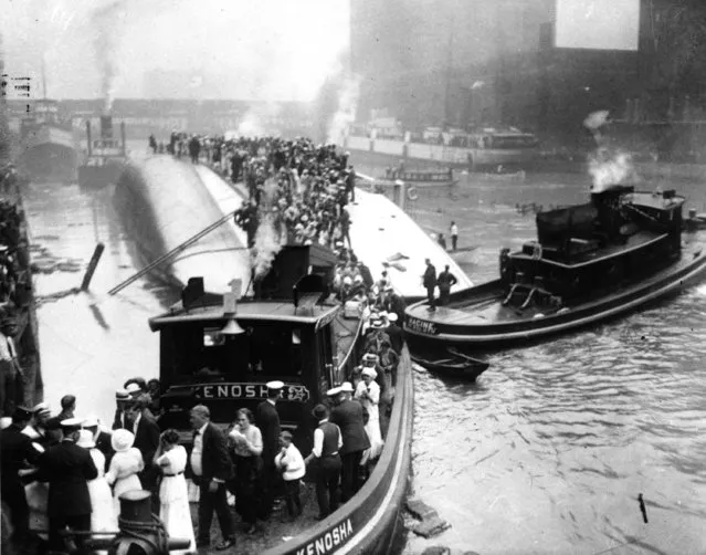 In this July 24, 1915 file photo, passengers are rescued as they stand atop The Eastland passenger ship after the vessel capsized in the Chicago River in downtown Chicago. As it was preparing to leave the dock, the Eastland rolled over, trapping passengers in the lower decks, where 844 drowned or were suffocated. On Friday, July 24, 2015 Chicago, historians and ancestors of the victims are marking the 100th anniversary of the disaster, the deadliest in city history. (Photo by AP Photo)