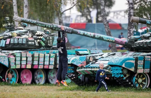 A boy hangs on the tank barrel during the Tank Biathlon competition at the International Army Games 2020 in Alabino, outside Moscow, Russia on September 2, 2020. (Photo by Maxim Shemetov/Reuters)