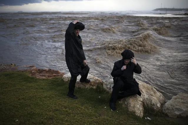 Ultra-Orthodox Jewish men stand next to a stream as it flows into the Mediterranean Sea during a rainstorm in the southern city of Ashdod November 26, 2014. (Photo by Amir Cohen/Reuters)