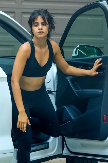 Makeup free Cuban-American singer Camila Cabello covers her belly as she steps out from a car in a sports bra and leggings to cast her vote in the ballot box in West Hollywood on October 13, 2020. The singer even made sure to wear her VOTE mask but had it upside down! (Photo by Backgrid USA)