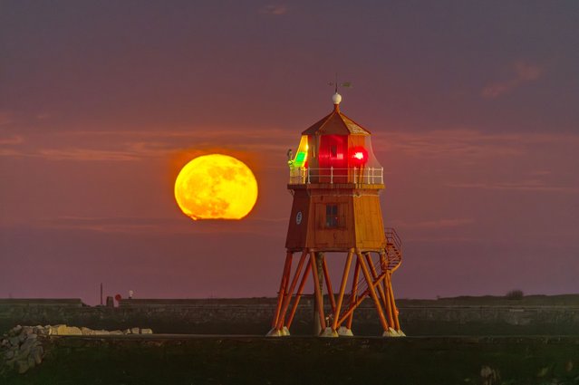 A pink moon – another name for the full moon in April – rises behind the Herd Groyne lighthouse on the River Tyne in North East England on April 25, 2024. (Photo by John Fatkin/Cover Images)