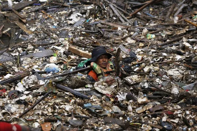 A volunteer clears rubbish from the Ciliwung River in the Jatinegara district of Jakarta, December 3, 2014. More than 1,000 soldiers and volunteers cleared 80 tons of rubbish after flooding hit parts of the capital last week, local media reported. (Photo by Reuters/Beawiharta)