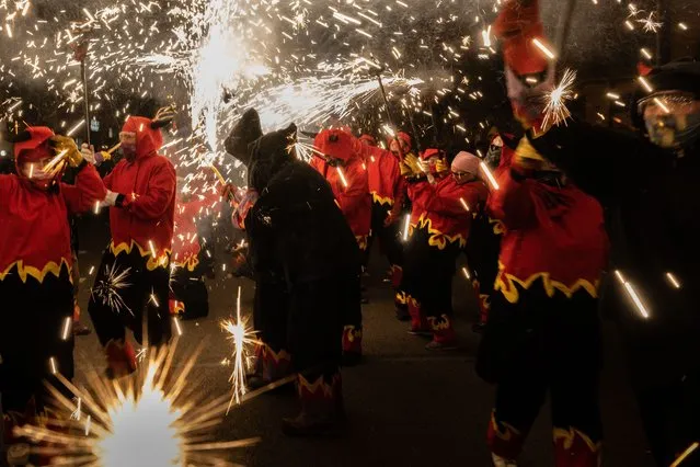 Revelers dressed up as devils hold torches with firecrackers as they take part in a “correfoc” or “fire-run” during the Sant Antoni neighborhood celebrations on January 23, 2022 in Barcelona, Spain. “Correfoc” is a traditional Catalan festival dated from the 12th century where people dress up as devils and dance among firecrackers. Spectators attempt to get as close as possible to the devils, running with the fire. (Photo by David Ramos/Getty Images)