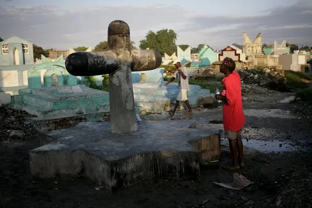 A voodoo believer prays at Baron Samdi cross in the cemetery of Croix des Bouquets, in the outskirts of Port-au-Prince, Haiti, November 1, 2015. (Photo by Andres Martinez Casares/Reuters)