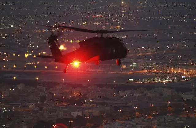 A UH-60 Blackhawk helicopter from Bravo Co 2/147th AVN Renegades flies support for U.S. Defense Secretary Chuck Hagel over Kuwait City December 8, 2014. Hagel flew out to Camp Buehring to visit with troops stationed there. (Photo by Mark Wilson/Reuters)