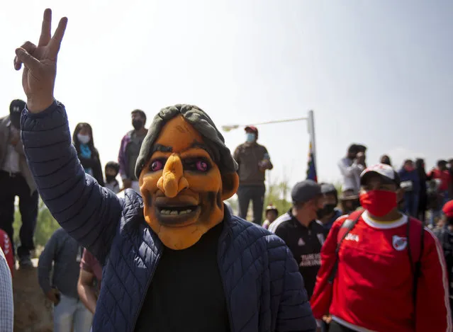 A man wears a puppet mask in the likeness of Bolivia's former President Evo Morales before a rally with Morales and Argentina's President Alberto Fernandez in La Quiaca, Argentina, Monday, November 9, 2020, on the border with Bolivia. Morales, who fled into exile after resigning last November, returned to his homeland the day after the presidential inauguration of his former finance minister Luis Arce. (Photo by Gianni Bulacio/AP Photo)