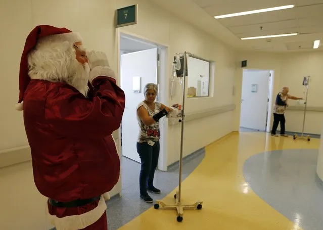 A man dressed as Santa Claus visits cancer patients who are undergoing chemotherapy at the Cancer Institute in Sao Paulo December 19, 2014. (Photo by Paulo Whitaker/Reuters)