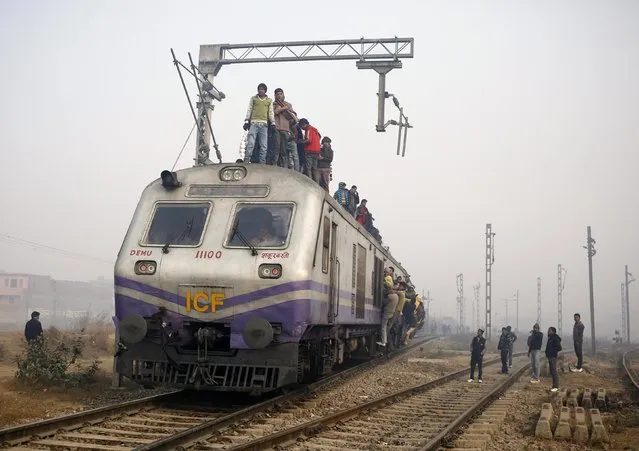 Passengers crowd atop a train as they travel on a cold winter morning at a railway station in Ghaziabad on the outskirts of New Delhi December 29, 2014. (Photo by Anindito Mukherjee/Reuters)