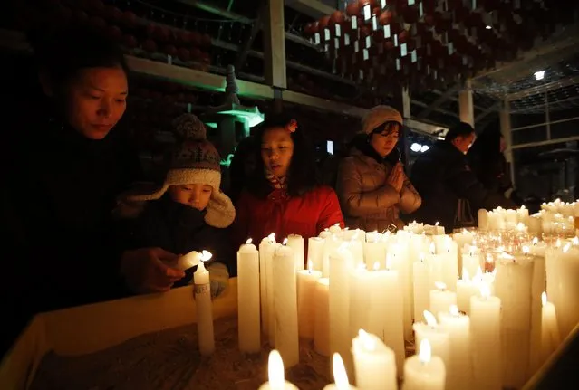 A boy lights a candle with his mother before a ceremony to celebrate the new year at Bongeun Buddhist temple in Seoul December 31, 2014. (Photo by Kim Hong-Ji/Reuters)