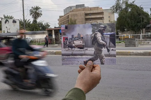 A photograph of car bomb attack on a U.S. military convoy in Baghdad, Iraq, Friday July 15, 2005, is inserted into the scene at the same location Tuesday, March 21, 2023, 20 years after the American led invasion on Iraq and subsequent war. (Photo by Hadi Mizban/AP Photo)