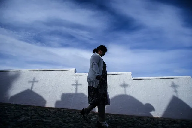 A woman walks in front of the shadows of tombs silhouetted on a white wall at the Cementery of Casabermeja in Malaga, southern Spain, 01 November 2016. Millions of Spaniards are visting cemeteries on the All Saints' Day to commemorate their deceased relatives and loved ones. All Saints' Day is observed on the 1st of November by the Roman Catholic Church and Protestant churches. (Photo by Jorge Zapata/EPA)