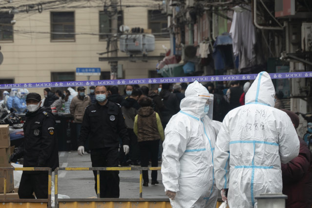 Police officers and workers in protective suits close off a neighborhood as it is placed under lockdown in Shanghai, China, Thursday, January 21, 2021. Shanghai has imposed lockdowns on two of China's best-known hospitals and some surrounding residential communities after they were linked to new coronavirus cases. (Photo by Chinatopix via AP Photo)