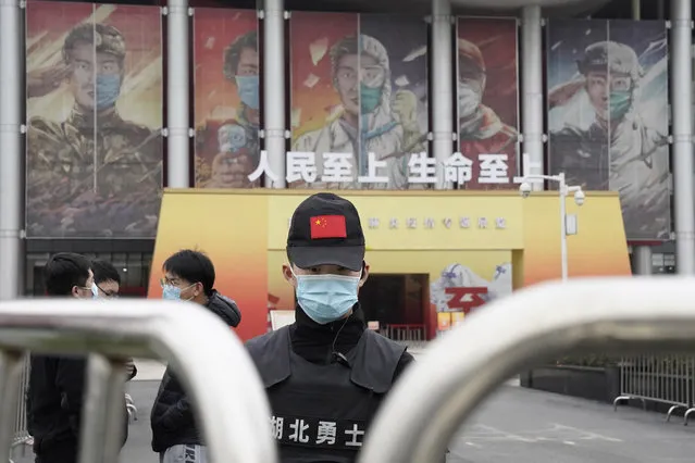 A security officer wearing a mask and a cap with the Chinese national flag guards the entrance after the World Health Organization team arrive at an exhibition about the fight against the coronavirus in Wuhan in central China's Hubei province on Saturday, January 30, 2021. The World Health Organization team investigating the origins of the coronavirus pandemic visited another Wuhan hospital that had treated early COVID-19 patients on their second full day of work on Saturday. (Photo by Ng Han Guan/AP Photo)