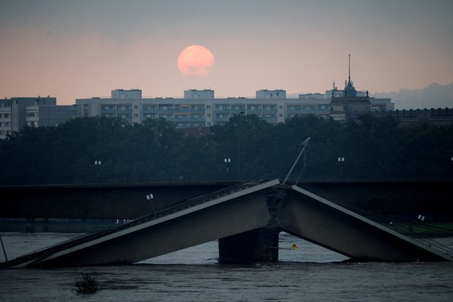 The sun rises over the partially collapsed Carola Bridge (Carolabruecke) on the flooding Elbe river in Dresden, Germany on September 17, 2024. (Photo by Matthias Rietschel/Reuters)