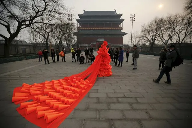 Chinese artist Kong Ning walks in her costume made of hundreds of orange plastic blowing horns during her art performance raising awareness of the hazardous smog in front of the Drum tower in a historical part of Beijing on a very polluted day December 7, 2015. (Photo by Damir Sagolj/Reuters)