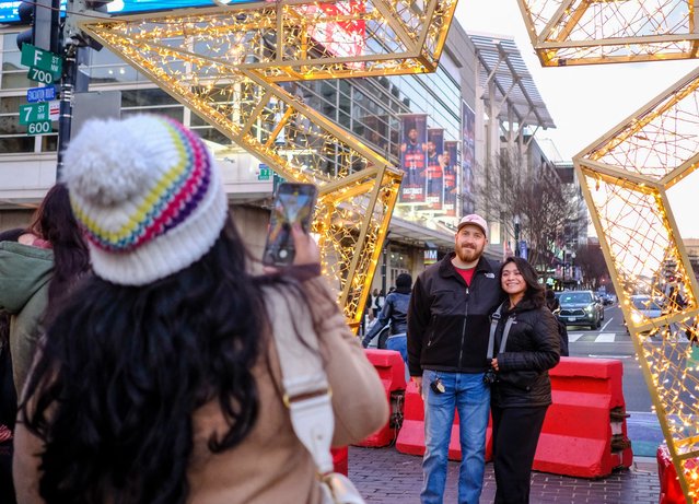 People take photos at a Christmas market in downtown Washington, DC, December 21, 2024. (Photo by Richard Pierrin/AFP Photo)
