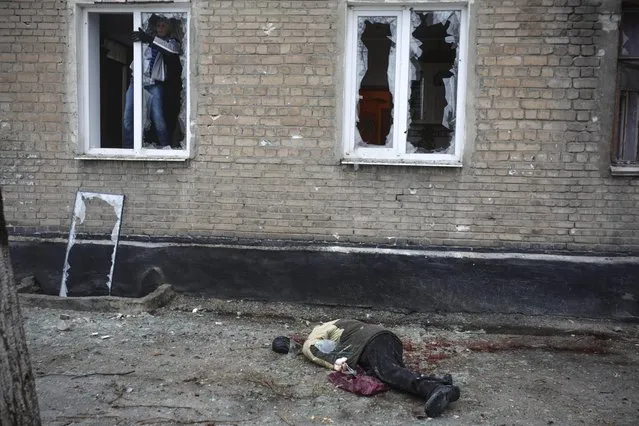 A body of a civilian killed when a mortar shell landed near a bus stop, lies on the ground in Donetsk, eastern Ukraine, Friday, January 30, 2015. Artillery fire in the rebel stronghold of Donetsk killed at least 12 civilians on Friday afternoon, the city hall in the rebel stronghold said, as fighting intensifies between pro-Russia separatists and government troops. (Photo by Vadim Braydov/AP Photo)