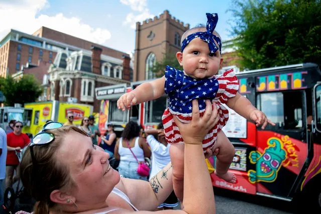 Amber Hess lifts her daughter, Emorie Narvaez, during Harrisburg’s Fourth of July food truck festival at River Front Park in Harrisburg, Pennsylvania on July 4, 2023. (Photo by Mark Pynes/AP Photo)