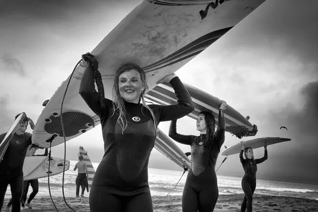 After an exhausting but satisfying surfing lesson on a stormy spring afternoon, a group of teens on a class trip walks back from the ocean carrying their surfboards on their heads. (Photo by Dotan Saguy)

