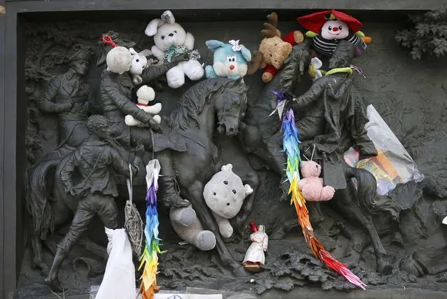 Stuffed toys paying tribute to the victims of last year's January and November shooting attacks are placed amongst a frieze on the statue at the Place de la Republique in Paris, France, January 6, 2016. France this week commemorates the victims of last year's Islamist militant attacks on satirical weekly Charlie Hebdo and a Jewish supermarket with eulogies, memorial plaques and another cartoon lampooning religion. (Photo by Charles Platiau/Reuters)